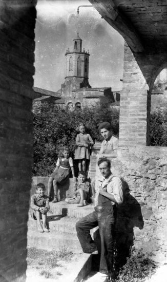 Retrat de grup de cos sencer a de Sant Mori. Al fons, la part superior de la torre del campanar de l'església de Sant Maurici. El noi recolzat a la paret és Jordi Brunet Forasté, 1946 (ACGAX. Fons Sadurní Brunet Pi. Autor: Sadurní Brunet)